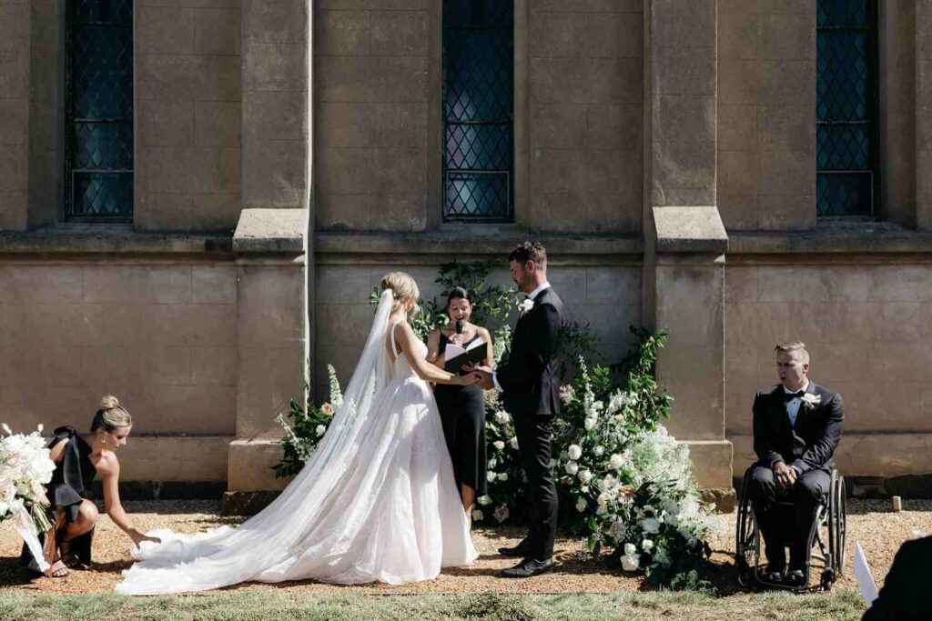 A bride and groom holding hands as they exchange vows outside a church