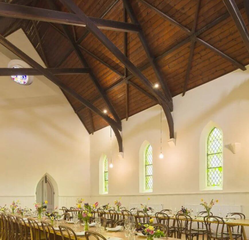 Two rows of tables with blooms on top inside a church