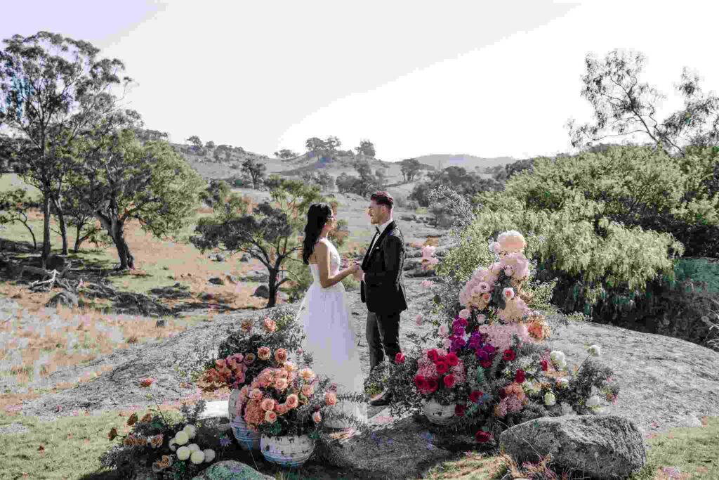 A couple outside at the altar surrounded by flowers