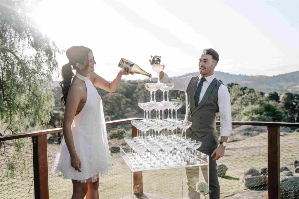 A couple pouring champagne into a tower