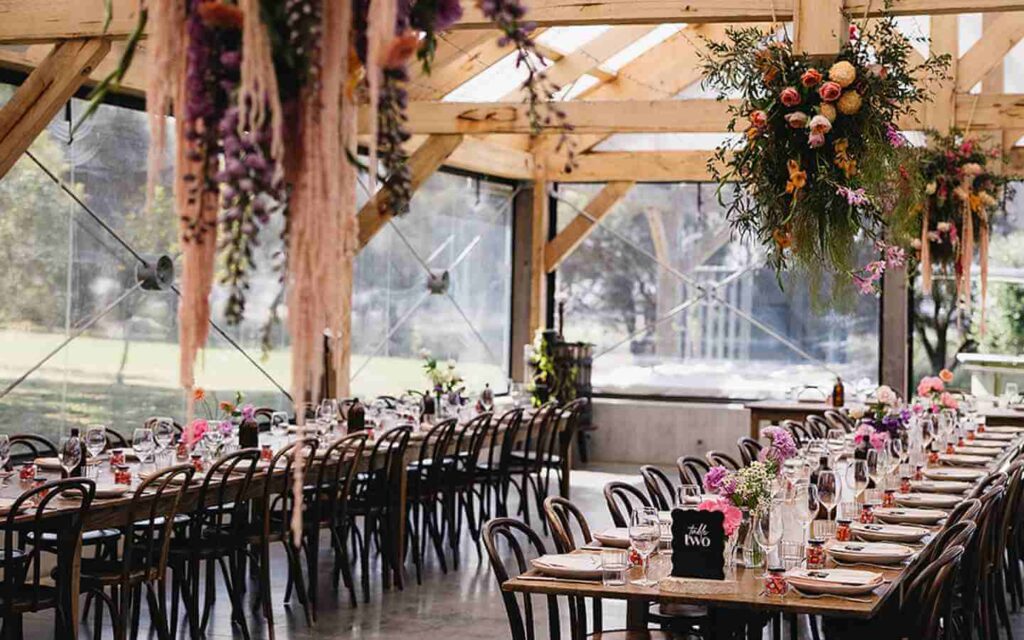 Tables at wedding below floral features suspended from ceiling