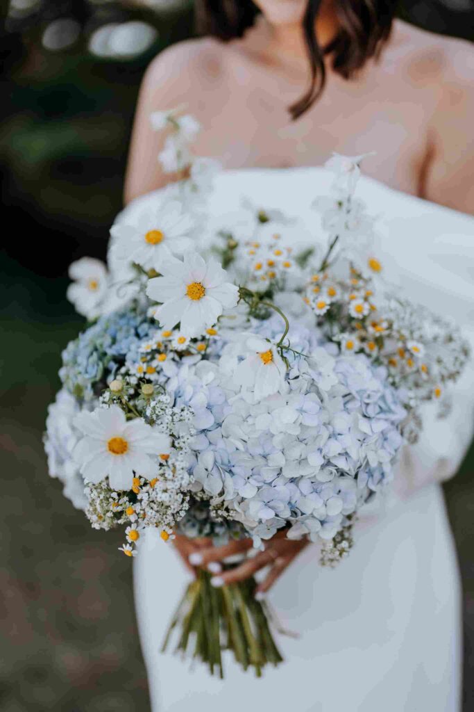 Bride holds a bouquet of white and blue posies