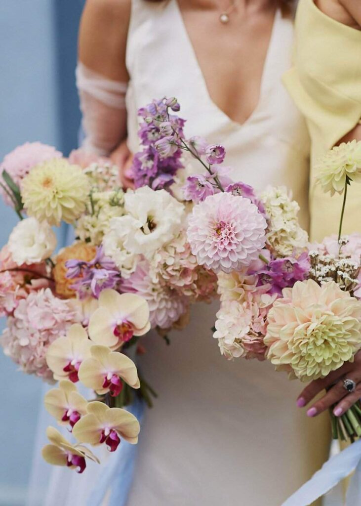 Bride holds wedding bouquet featuring orchids and purple flowers in cool tones