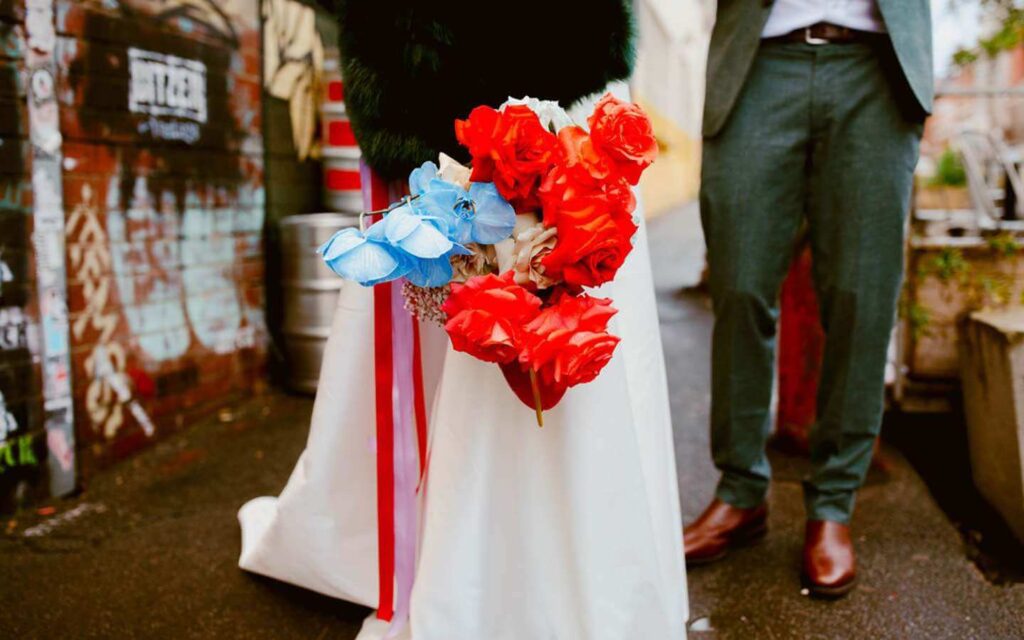 Blue and red bridal bouquet held by Bride in alley way
