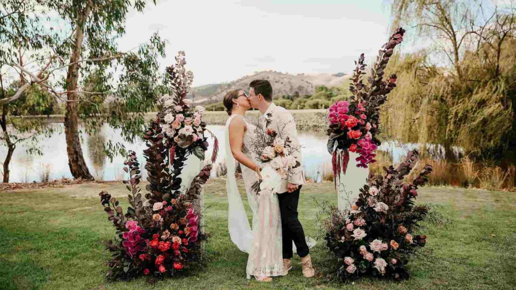 bride and groom kissing at cermeony setting with colourful flowers
