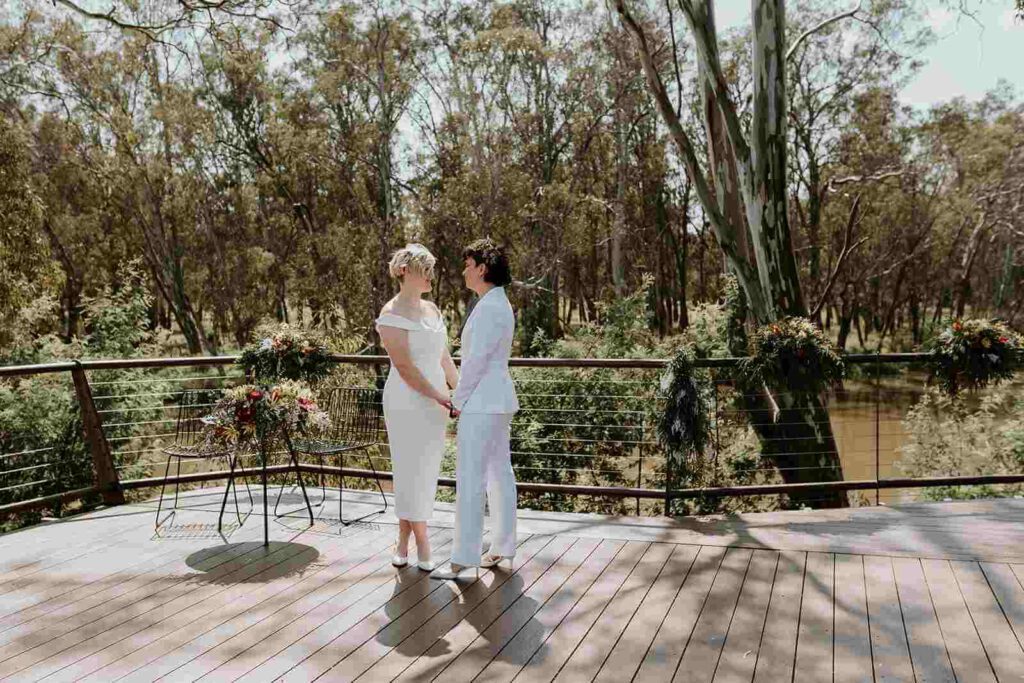 two brides holding hands standing on timber decking