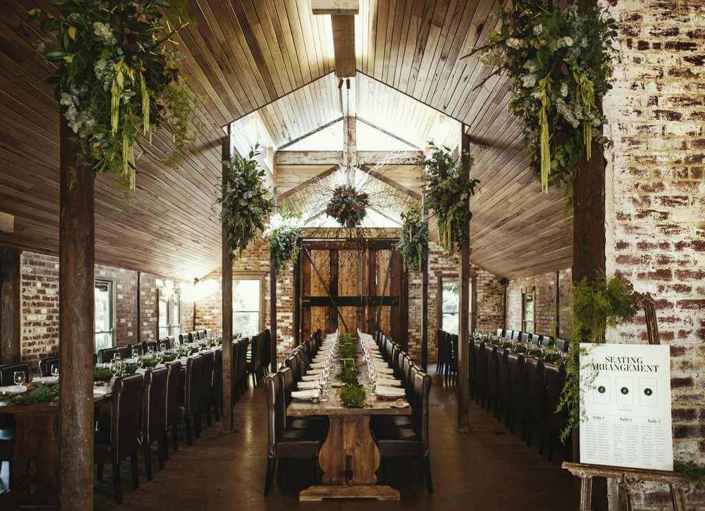 timber and brick barn setting with table. chairs and greenery