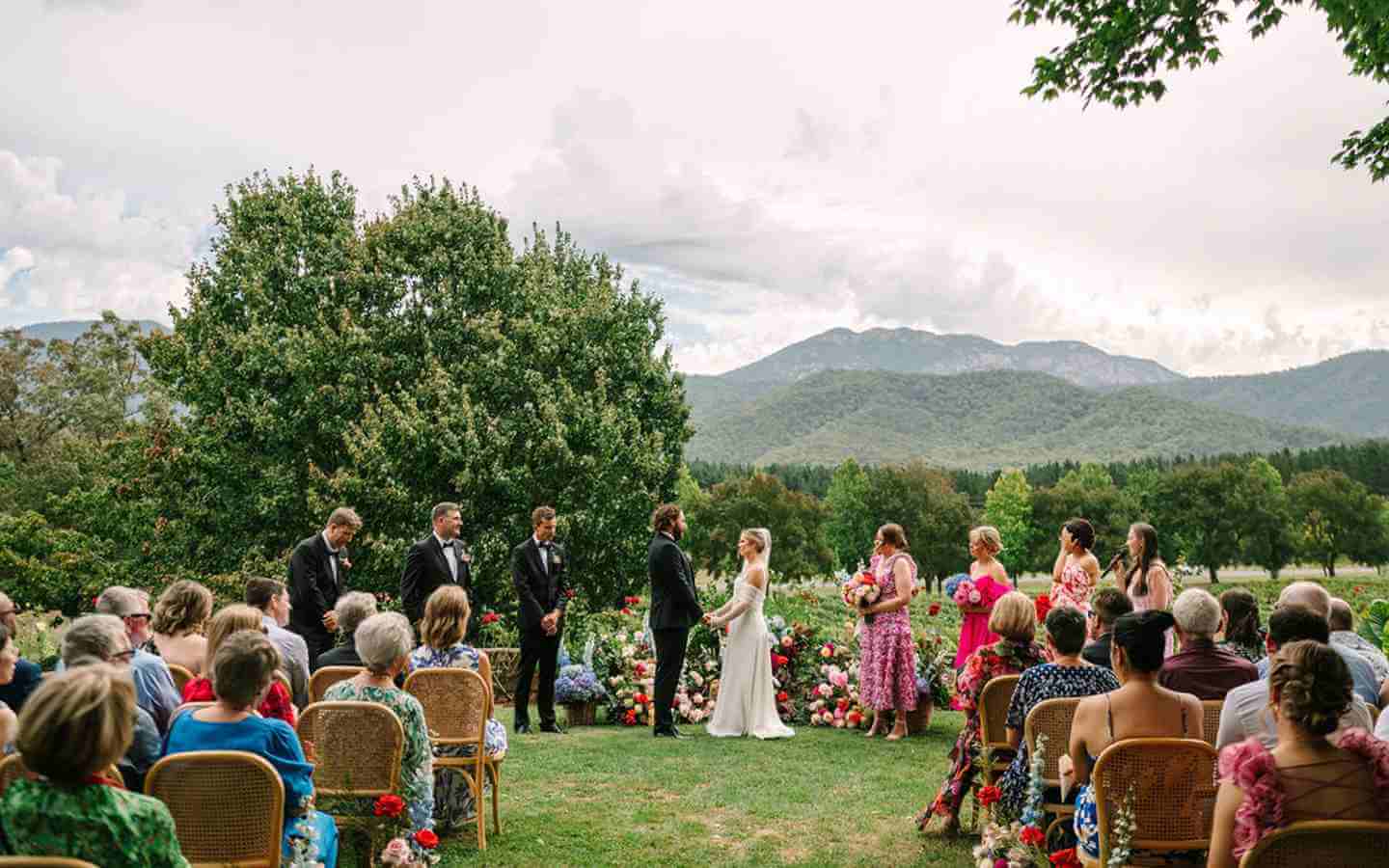 Bride and groom standing at ceremony with guests and wedding party with mountain views