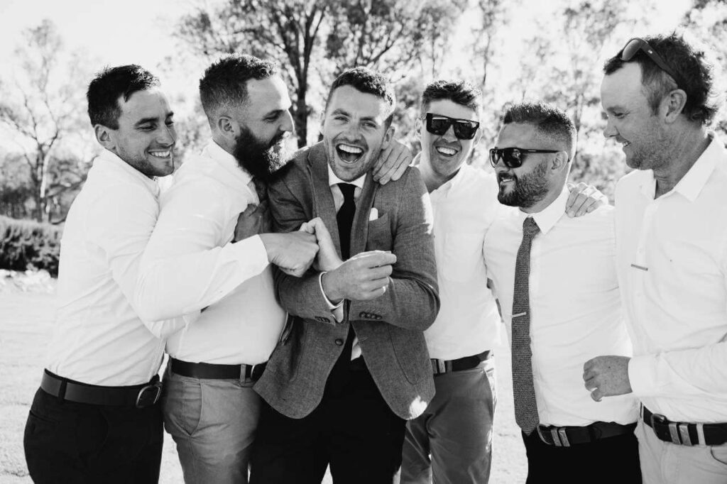 groom with groomsmen ith arms around each other standing outside