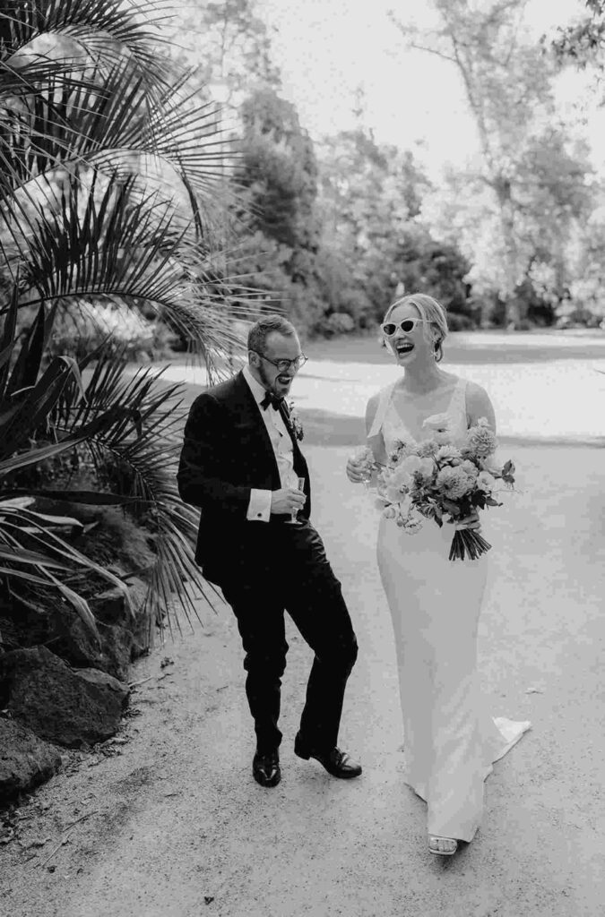 bride and groom walking down driveway laughing