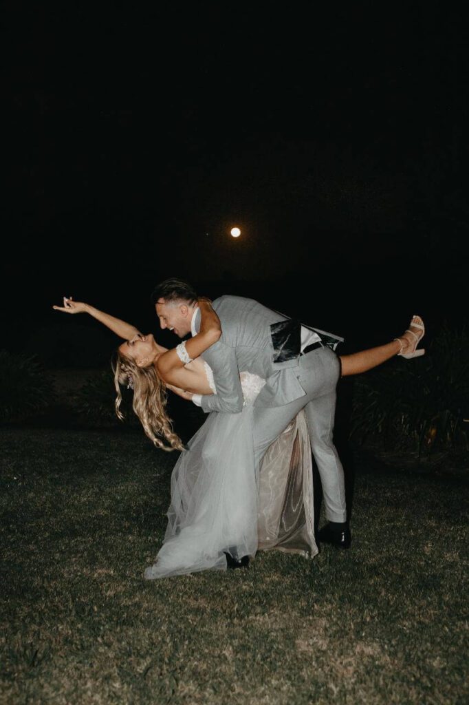 bride dipped by groom on grass with leg up