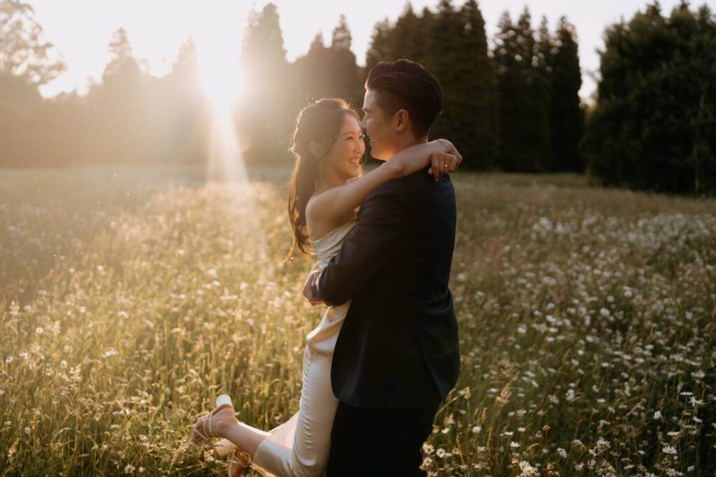 A bride and groom embracing each other in a field of flowers on their wedding day.