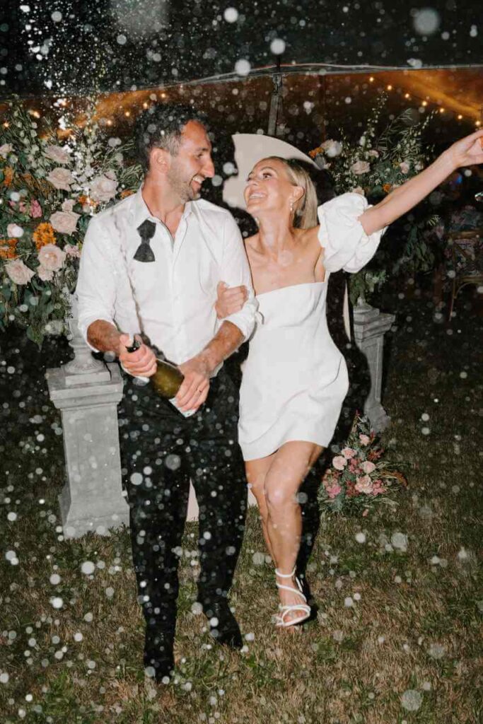 A bride and groom spraying champagne at their wedding reception.