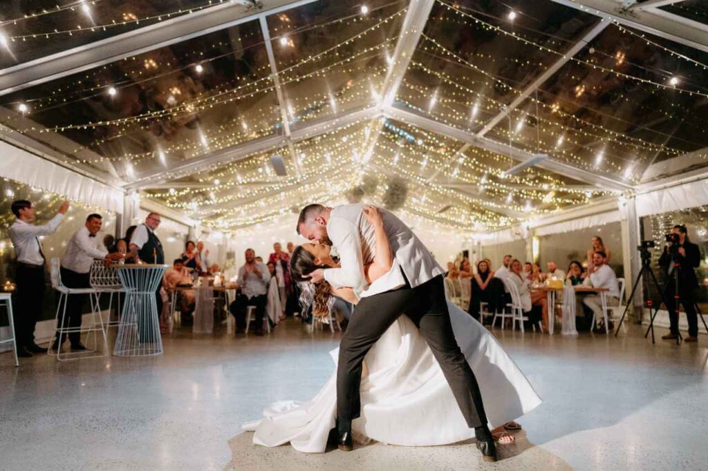 A bride and groom kissing on the dancefloor during their night time wedding reception.