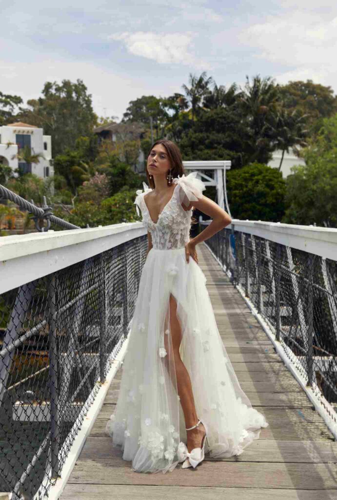 Bride poses in flowy embellished gown on wooden bridge