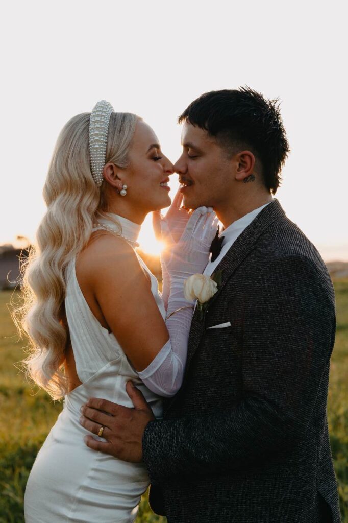 couple in paddock closeup with sun peeking through about to kiss