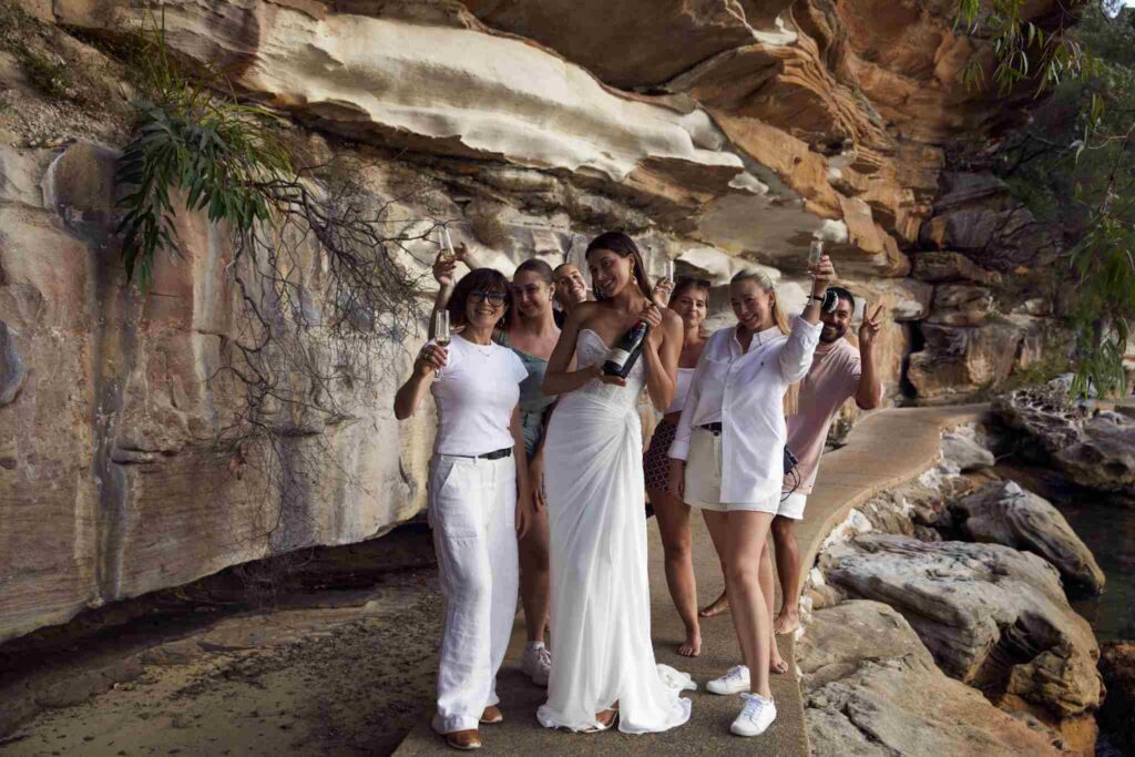 Bride posing for pictures with champagne and her designers 