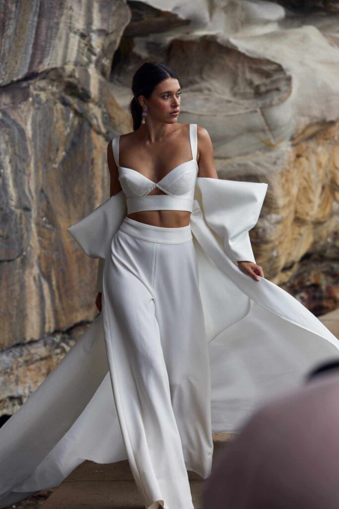 Bride walking through rocks wearing white wedding two piece