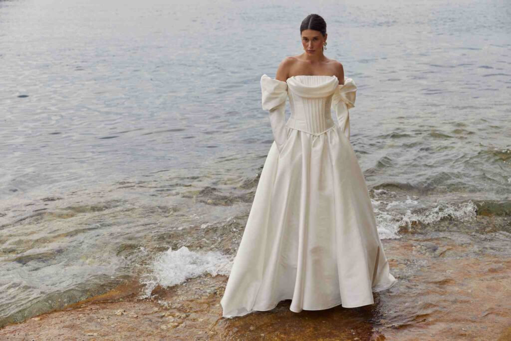 Bride poses for image as she stands in ocean water.