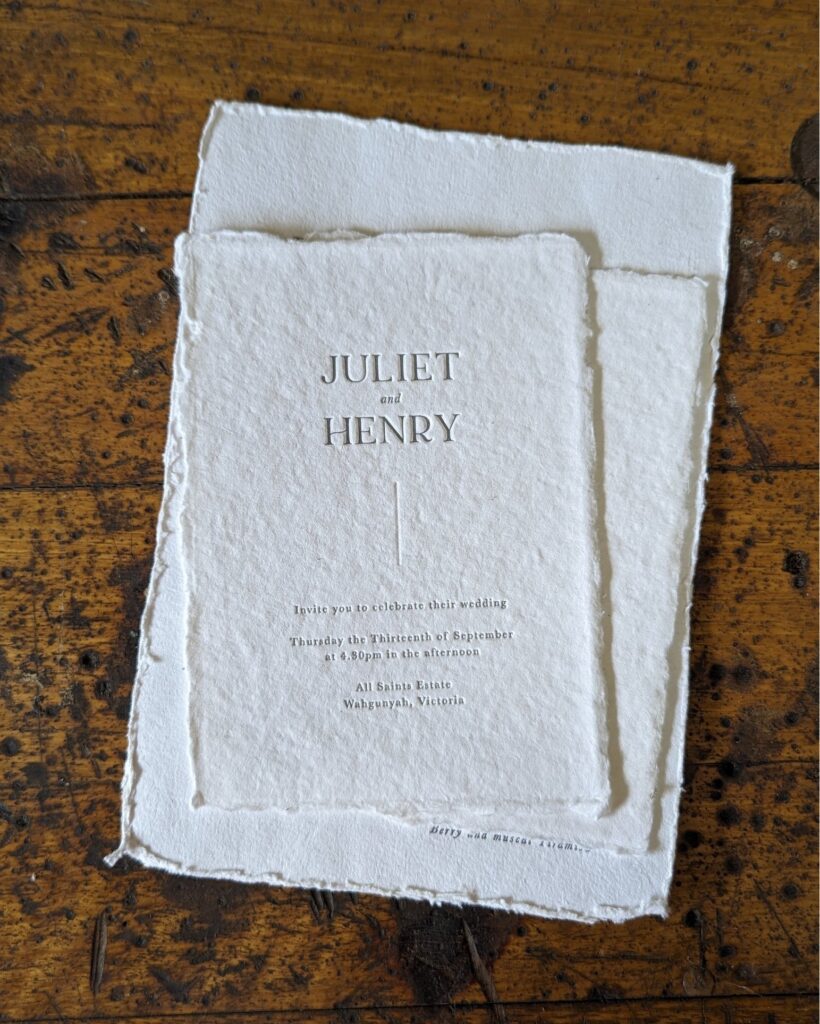 A couple’s wedding invitations lying on a wooden table.