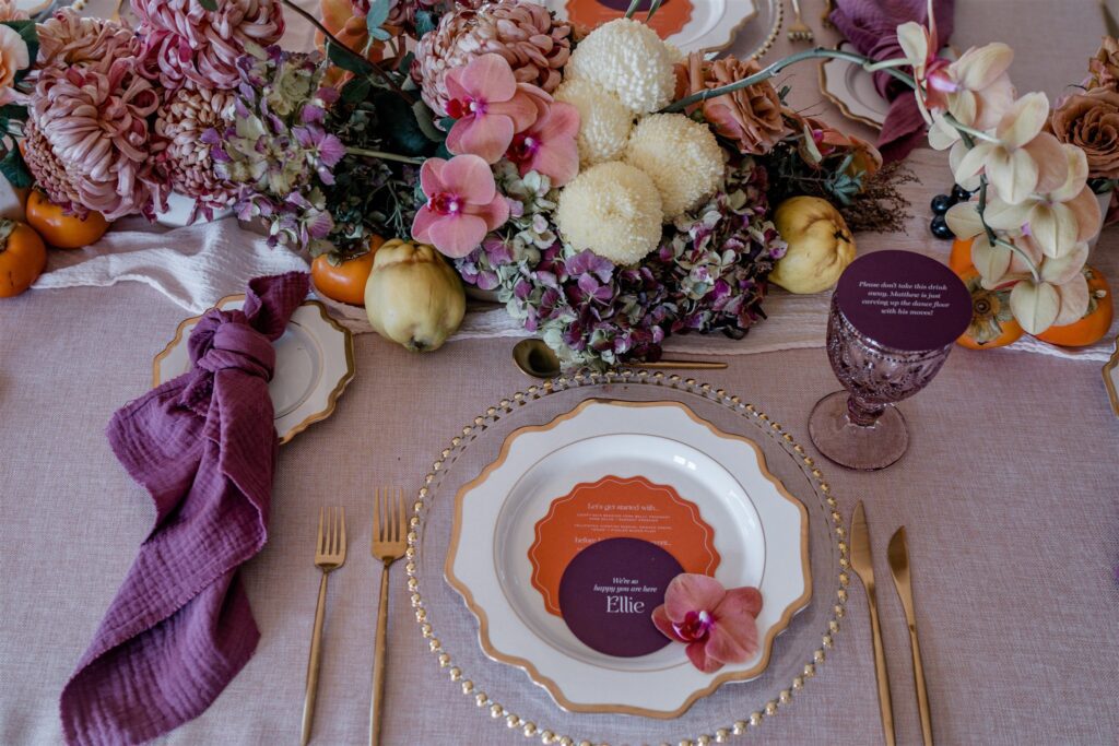 A table place card and wedding menu sitting atop a table setting.