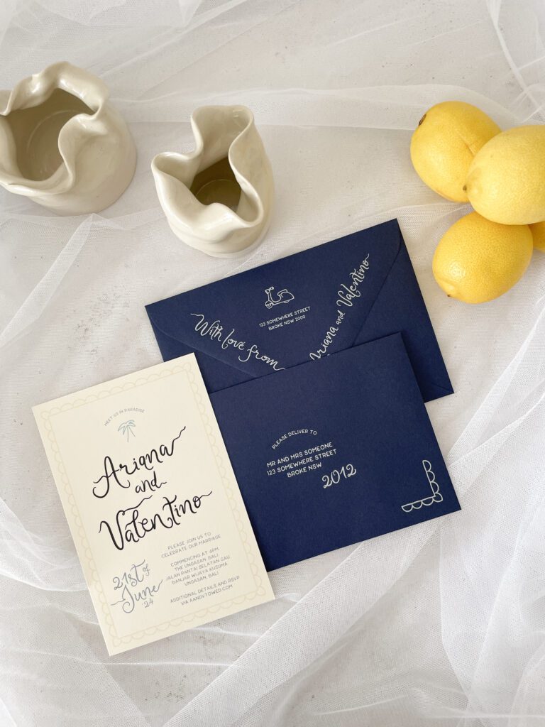 Navy-blue wedding invitations lying on top of tulle and next to lemons.