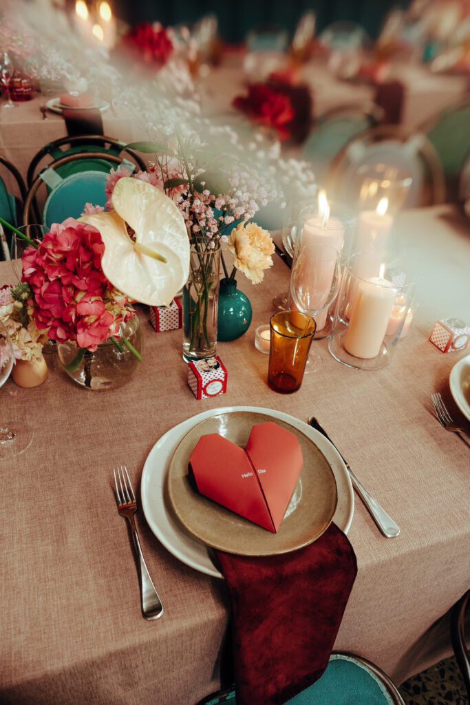 A wedding dinner table with an origami menu heart sitting atop a plate.