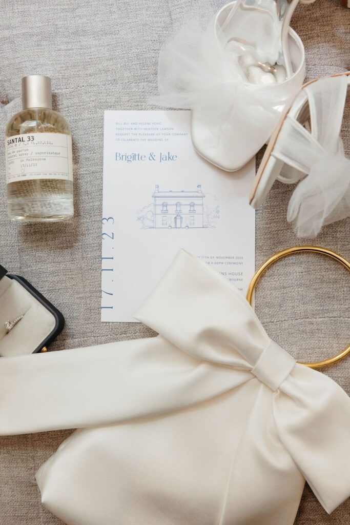 A wedding invitation lying atop linen and surrounded by white bows.