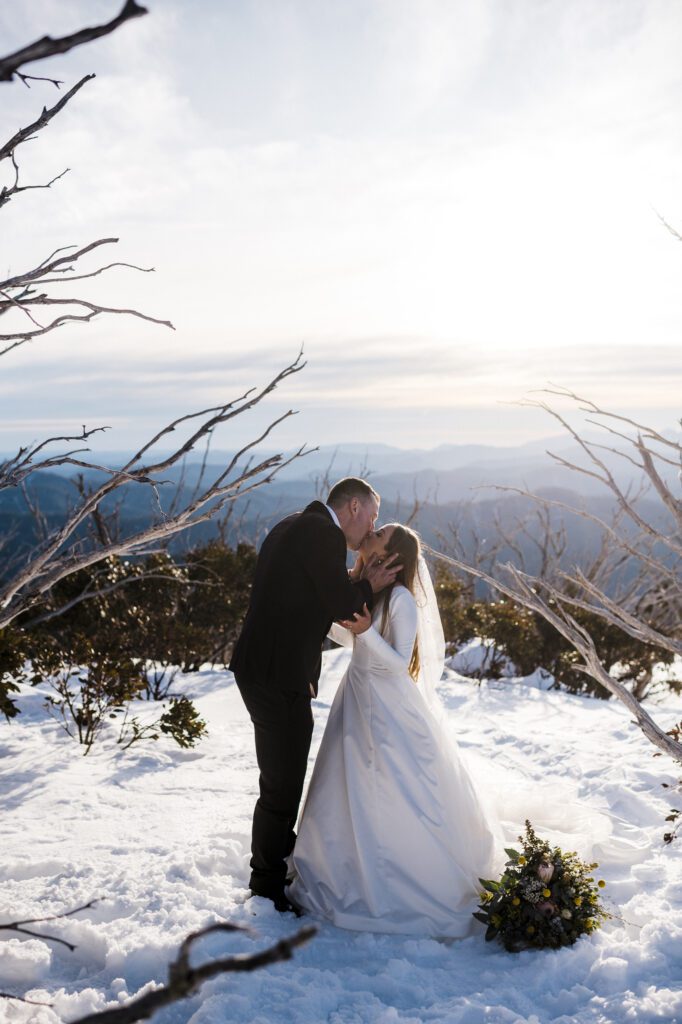 Groom kissing bride in snow