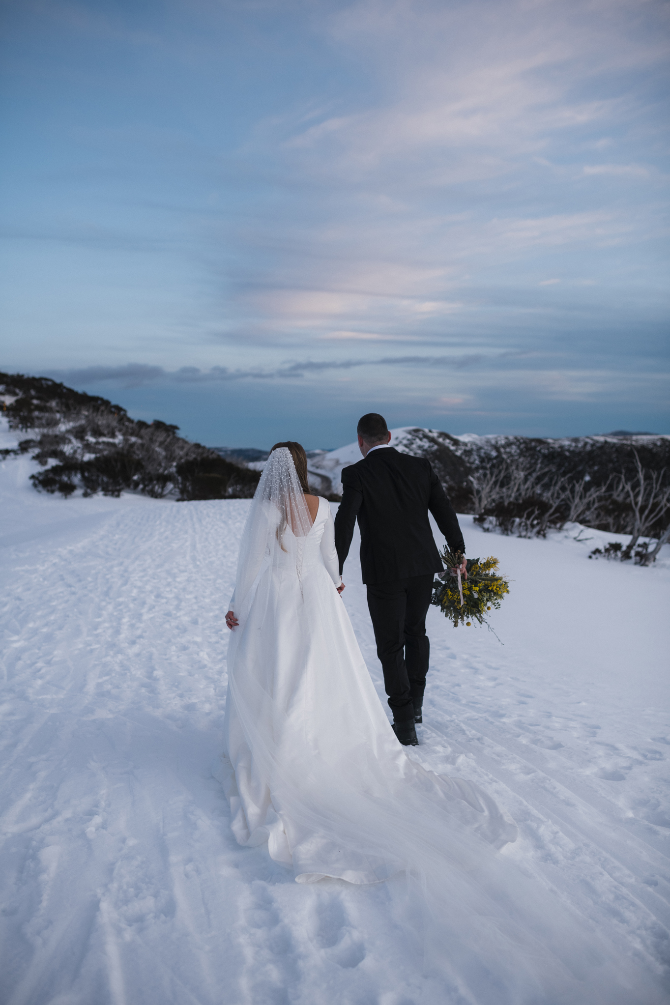 Couple walking in snow after wedding