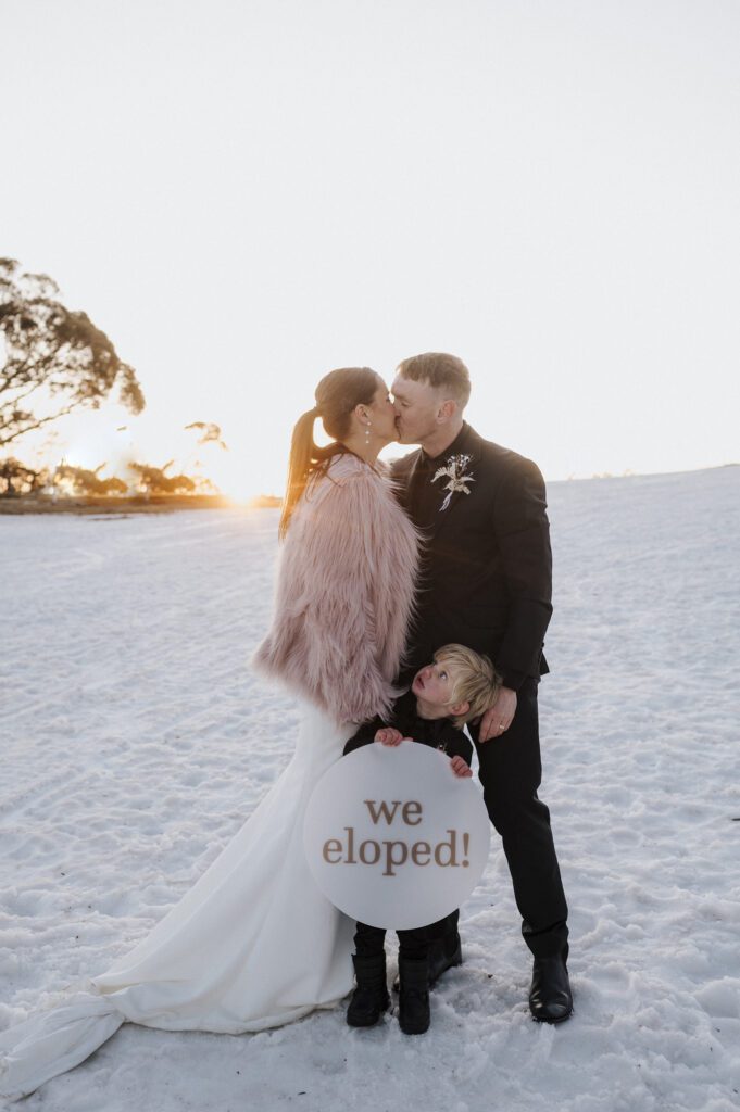 Bride and groom at snow with elope sign