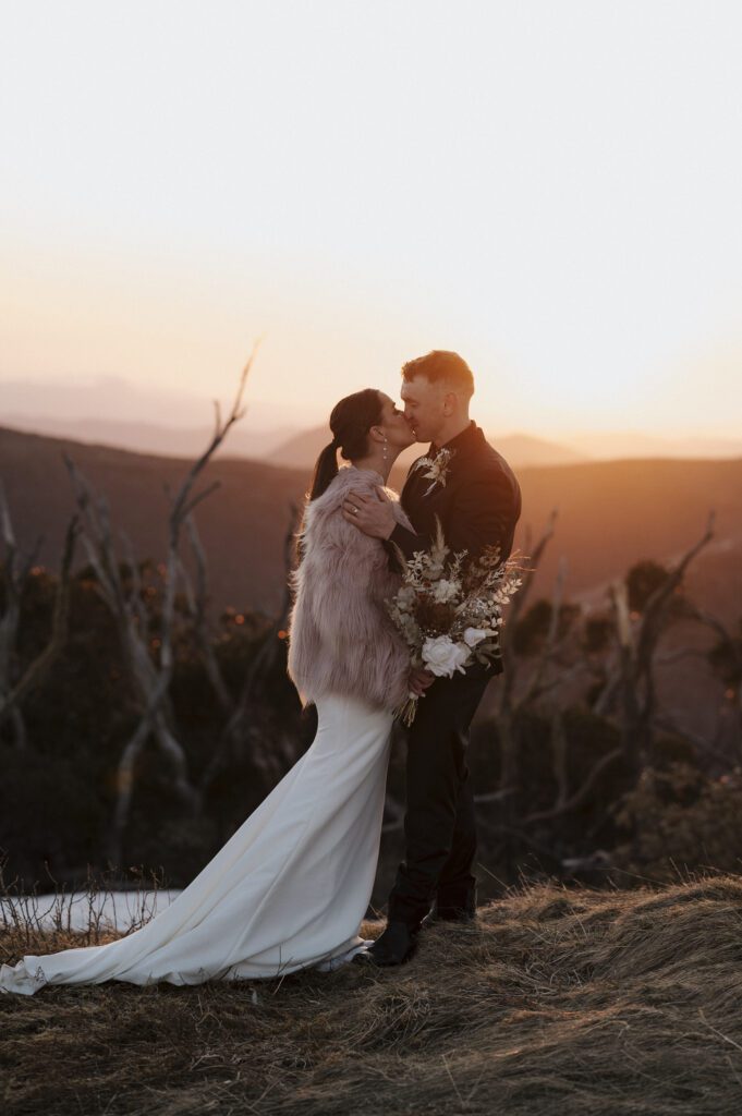 Bride and groom kissing at sunset