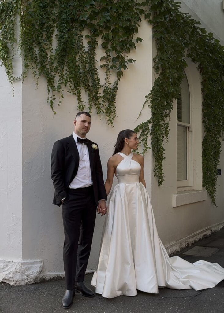 Bride and groom standing in front of white building